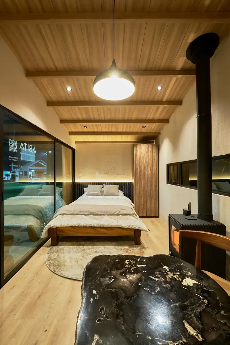Dormitorio con estufa a leña de la Casa Modular ABITA en Expodeco